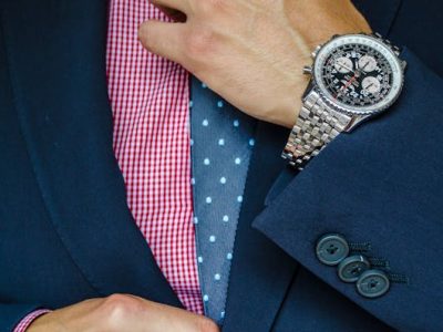 hombre acomodandose la corbata con un buen reloj
