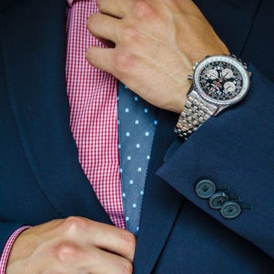 hombre acomodandose la corbata con un buen reloj