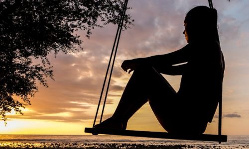 mujer triste mirando un atardecer