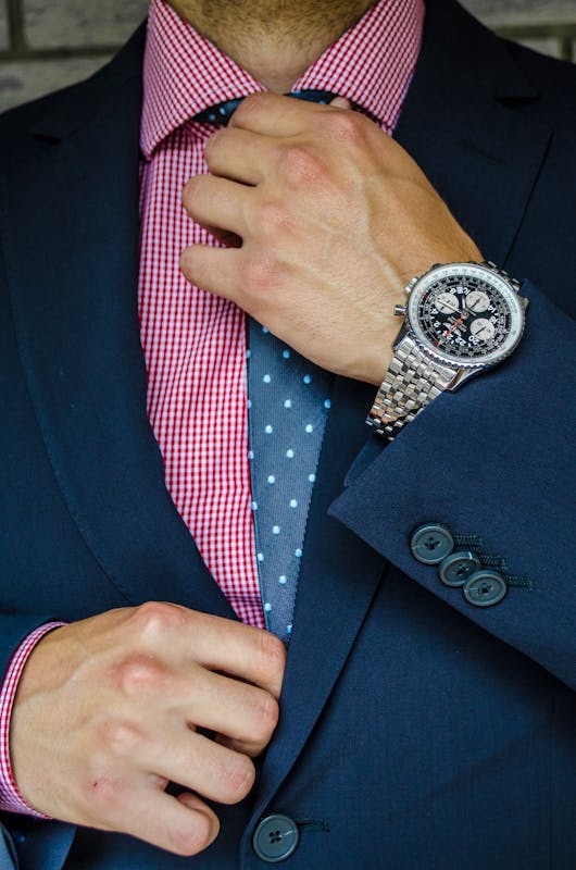 hombre acomodandose la corbata con un buen reloj