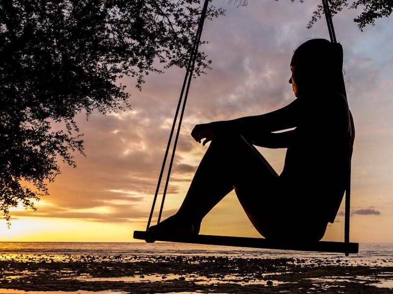 mujer triste mirando un atardecer